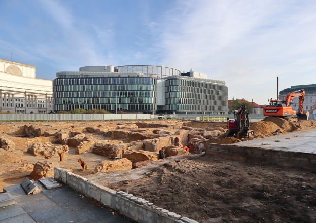 Baustelle in Berlin, Deutschland, mit einem großen Gebäude im Hintergrund, Fahrzeugen, Arbeitern und Materialien während des Baus der Berliner Mauer.