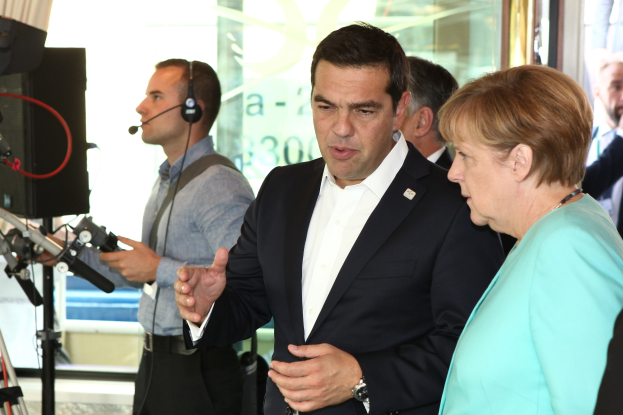 Bundeskanzlerin Angela Merkel und Joachim Gauck vor einer Glaswand mit Vorhang, in Anzüge gekleidet und in Mikrofone sprechend.