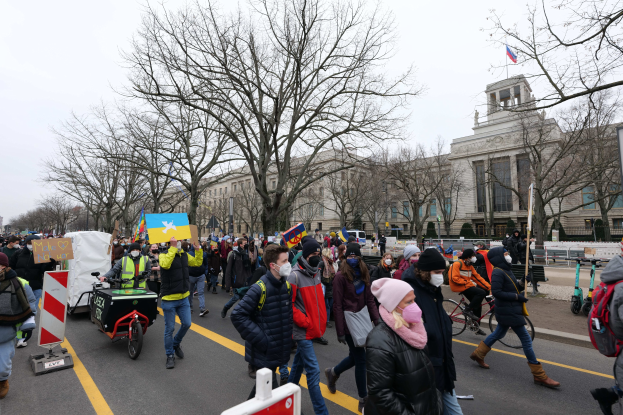 Eine große Gruppe von Menschen marschiert auf einer Straße in Washington, D.C. am 21. Januar 2020 mit Schildern, Transparenten und Fahrrädern, mit Bäumen, Schildern und einem klaren blauen Himmel im Hintergrund.
