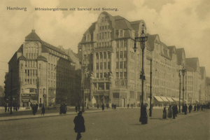 Ein altes Schwarz-Weiß-Foto von Menschen, die eine Straße in Hamburg, Deutschland, entlanggehen, gesäumt von Gebäuden, Straßenlaternen, Straßenlaternen und Kraftfahrzeugen unter einem bewölkten Himmel mit Text oben.