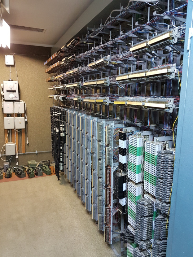 Großer Raum voller Server, Kabel und elektronischen Geräten, typisch für eine Rechenzentrumsanlage.