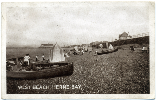Schwarzes und weißes Foto von Menschen am Weststrand in Herne Bay, mit Booten im Vordergrund, H├Ąusern und einem Zaun im Hintergrund und Text unten.
