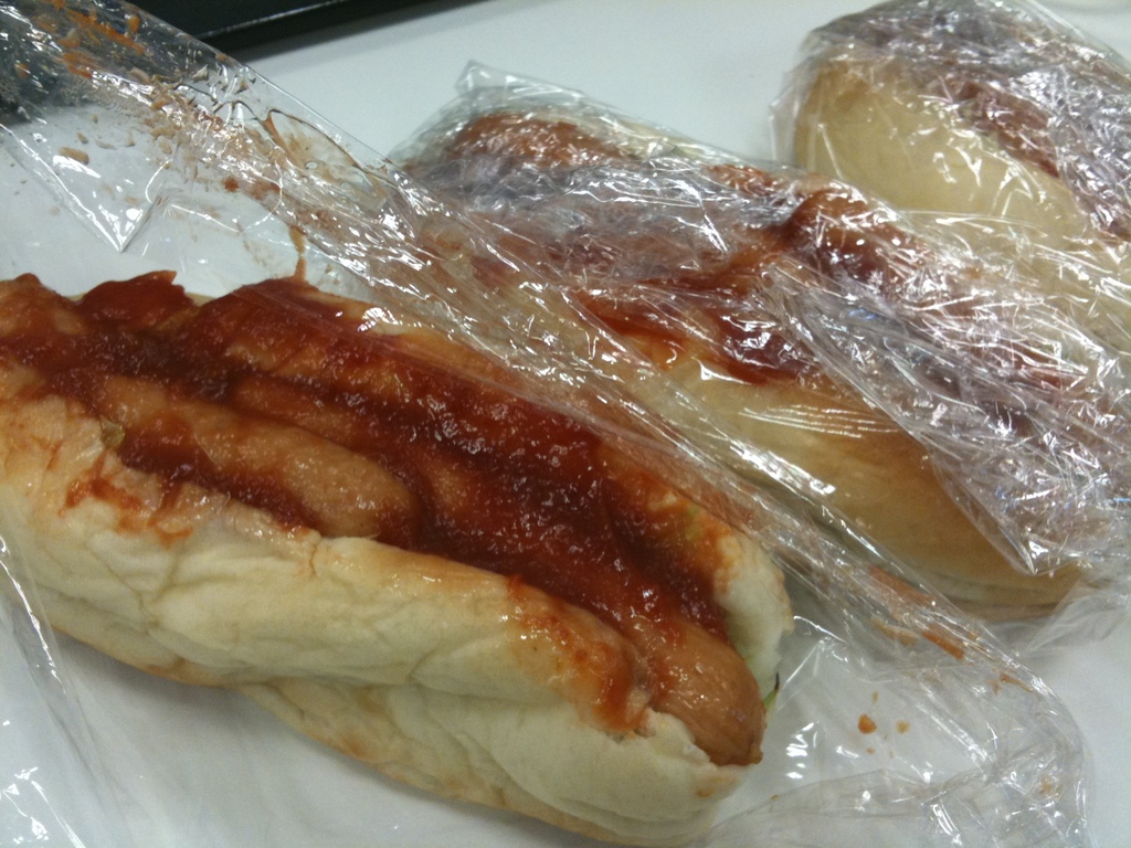 Ein Tisch mit Sandwiches, Hotdogs und Ketchup in der Mitte.