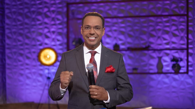 Stephen Colbert, Moderator von *The Daily Show with Trevor Noah*, steht auf einer Bühne und hält ein Mikrofon in der Hand, während er einen Anzug, eine Krawatte und eine Brille trägt.