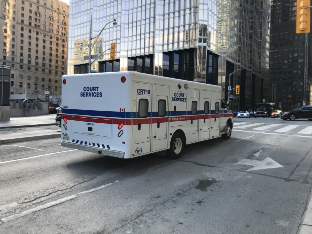 Ambulanz auf einer Stadtstra├če mit hohen Geb├Ąuden, Stra├čeninfrastruktur und Passanten im Hintergrund.