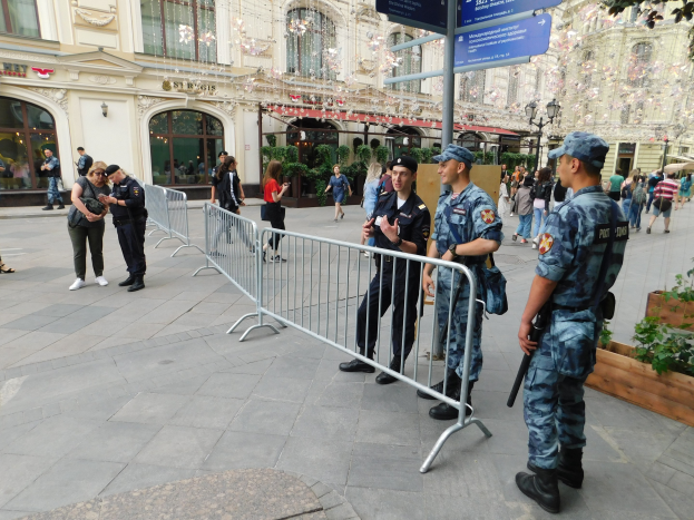 Polizeibeamte in Uniform stehen hinter Barrieren und blicken auf eine Menge, einige tragen Mötze und halten Waffen, mit Schildern und Gebäuden im Hintergrund in Wien während einer Anti-Terror-Operation.