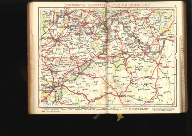 Ein aufgeschlagenes Buch mit einer detaillierten Deutschlandkarte, die Straßen und Autobahnen zeigt, vor einem schwarzen Hintergrund.