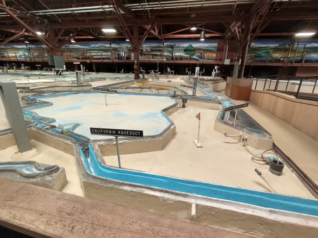 Indoor-Wasserpark mit mehreren Wasserrutschen, Deckenbeleuchtung, Wandgemälden und einem Minigolfplatz.