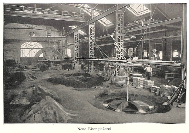 Schwarzes und weißes Foto eines Fabrikinneren mit Arbeitern, die Maschinen bedienen, Metallstangen und -pfähle, beschriftet mit "Neue Eisenglebeerei, die erste Fabrik Deutschlands" unten.
