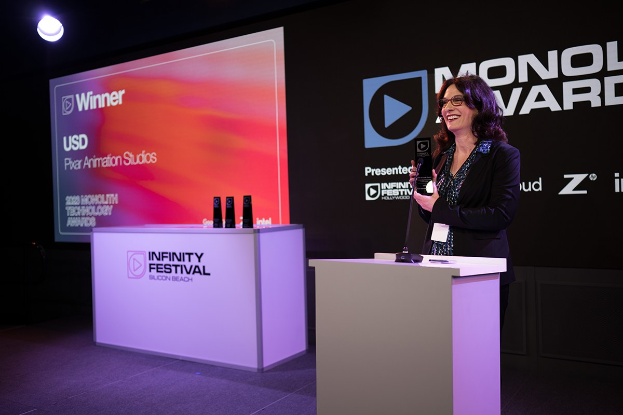 Frau in einem schwarzen Kleid, die einen Preis auf einem Podium mit einem Mikrofon hält, spricht bei der Monolux Awards-Veranstaltung 2020.