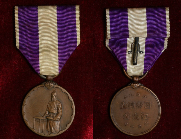 Zwei Medaillen mit lila und weißen Bändern auf einem rotbraunen Hintergrund, jeweils mit Inschrift.