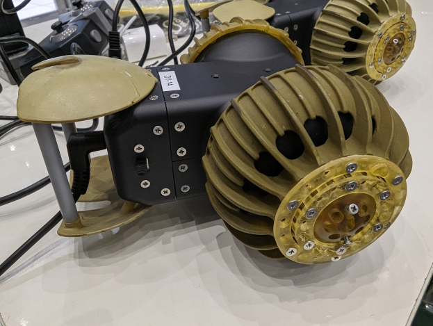 Nahaufnahme eines schlanken, metallischen 3D-gedruckten Roboters auf einem Tisch umgeben von Kabeln.