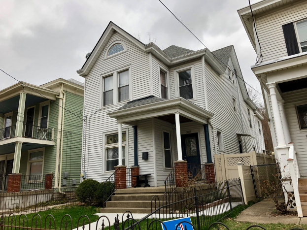 Reihe von Häusern mit Fenstern, Türen, Säulen, Geländern, Stufen und Dächern, umgeben von einem Metallzaun, Gras, Pflanzen, Bäumen und einem bewölkten Himmel, mit einem Mietschild unten, das das Objekt unter der Adresse 5901 S Elmwood Ave, Chicago 60618 auflistet.