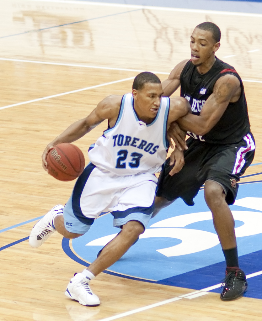 Zwei Personen spielen Basketball, eine hält den Ball.