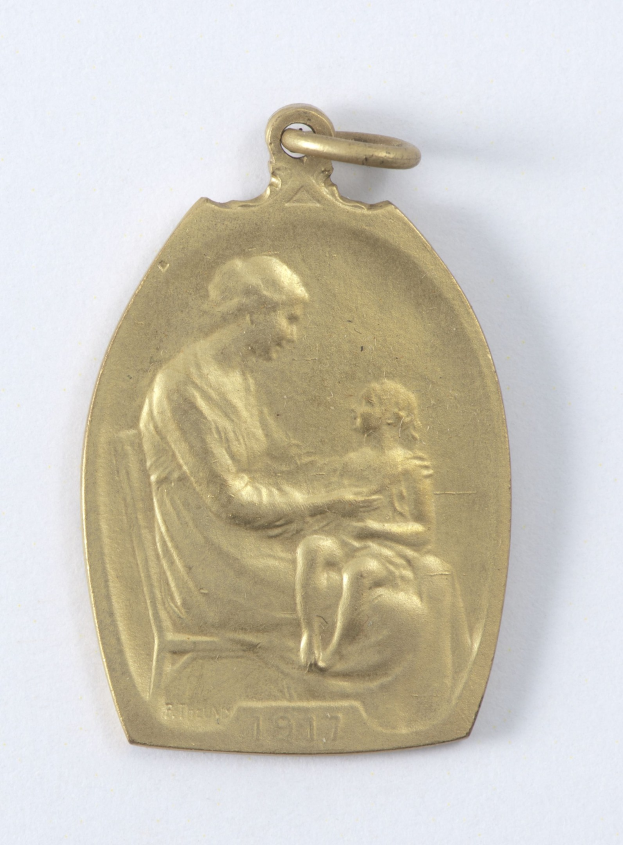 Goldmedaille mit Relief einer Frau in weißem Kleid mit Haarknoten, die ein Kind hält, beide schauen sich sanft und neugierig an, beschriftet mit 'Mutter und Kind' in Schreibschrift.