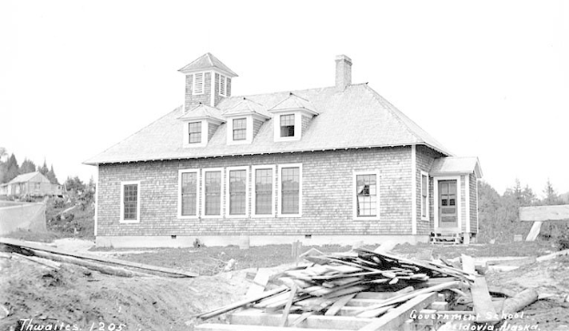 Schwarz-weißes Foto eines Regierungsgebäudes aus dem Jahr 1905, umgeben von Bäumen unter einem klaren Himmel, mit Holzplanken und Text unten, der 'Regierungsgebäude, Thwaites, 1905' lautet.